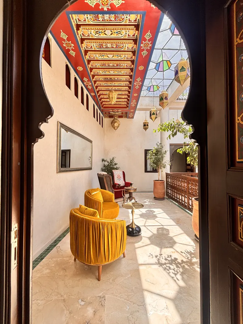The gallery salon seen through the arch: ochre armchairs under the painted ceiling