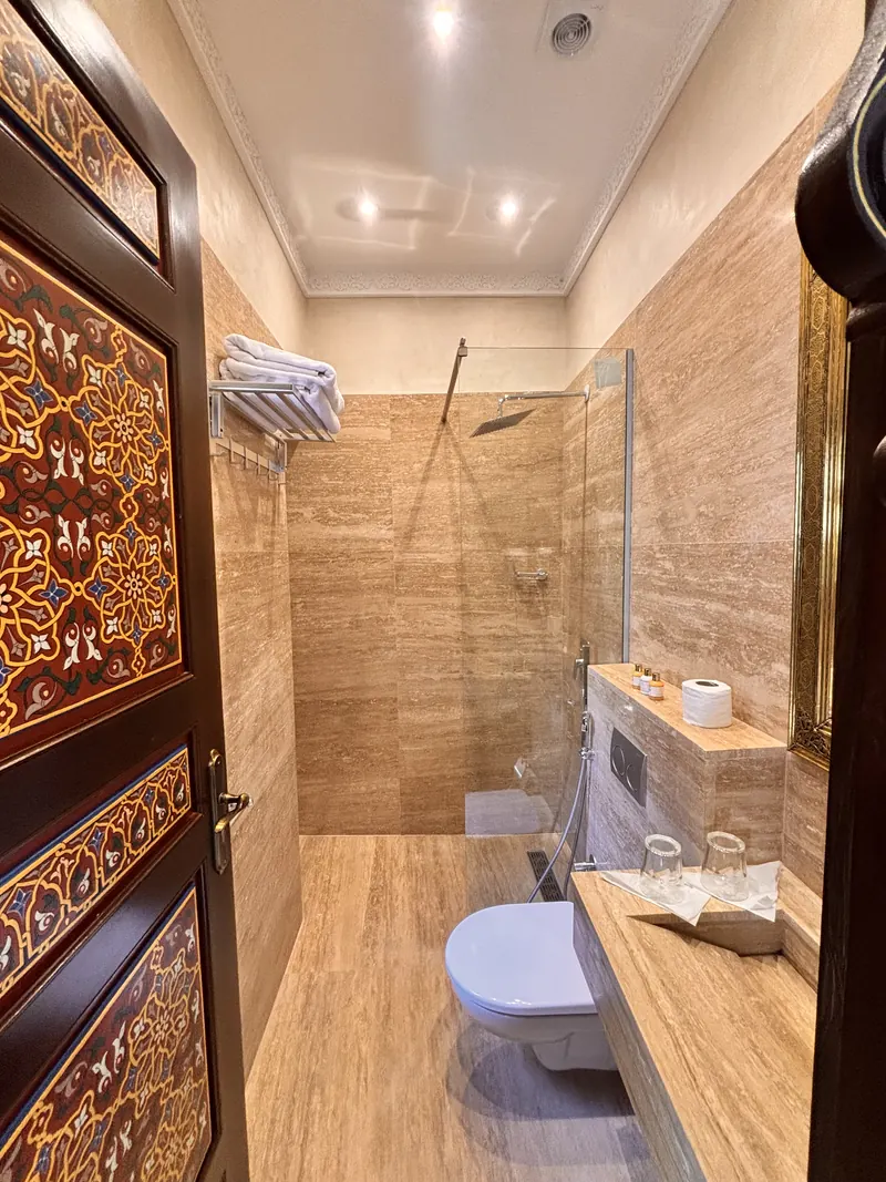 Private bathroom in travertine, walk-in shower and painted door