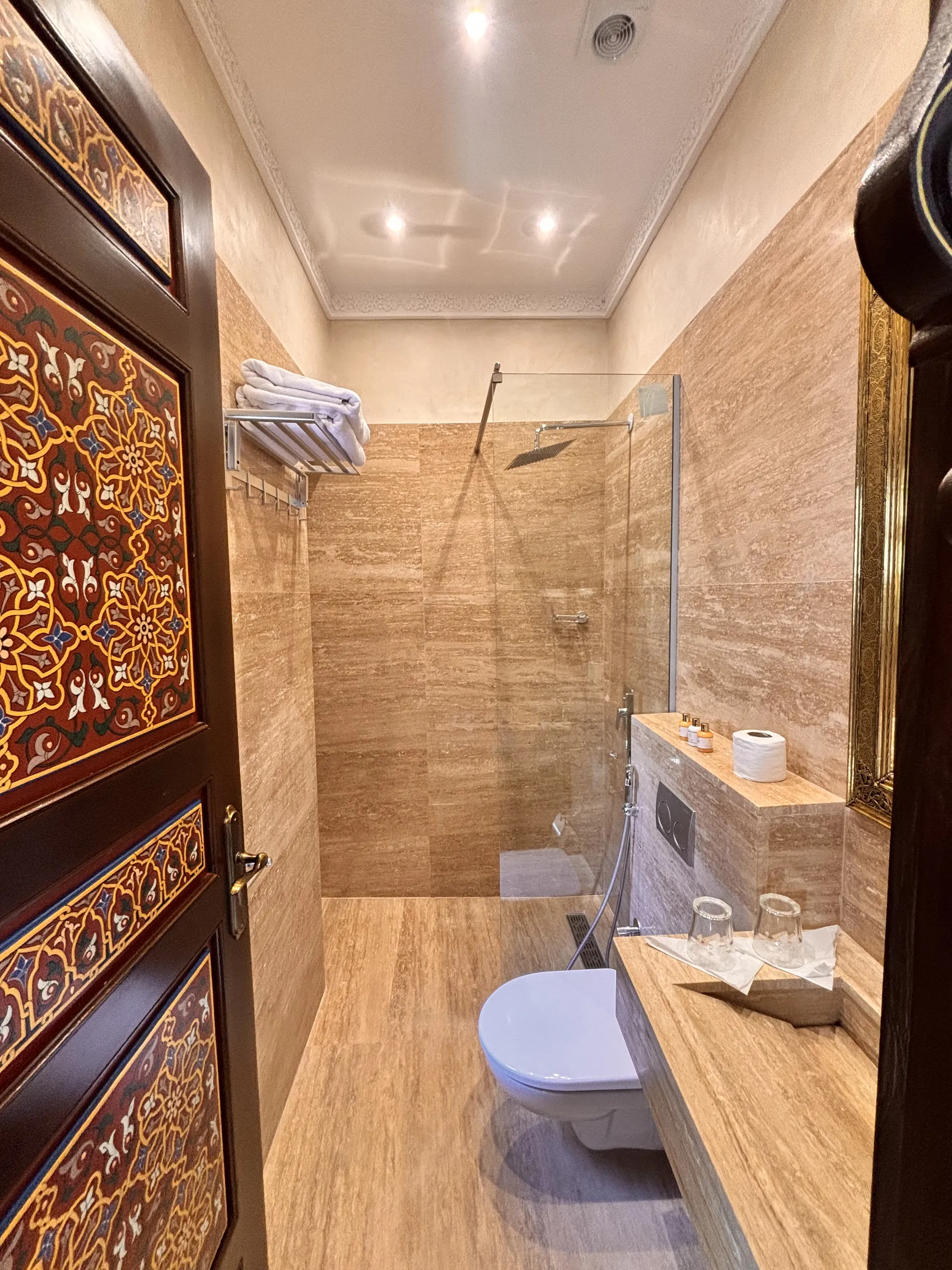 En-suite shower room in travertine with rain shower and painted door